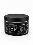 A black tin of Hampshire Wick natural soy wax candle in the Cherry Blossom & Plum scent, shown on a clean white background with a subtle reflection.